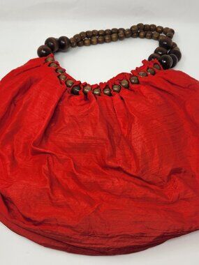 New red sling cloth handbag with light brown beads and a dark brown bead handle.